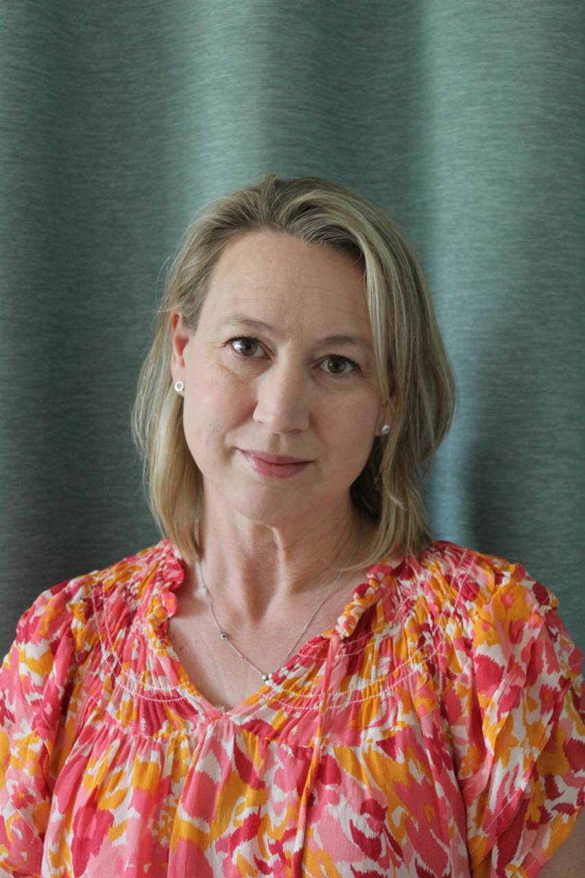 Jennie Edvardsson, Sustainable Transport Business Manager bei Scania, steht vor einem blauen Vorhang in einer Blumenbluse.