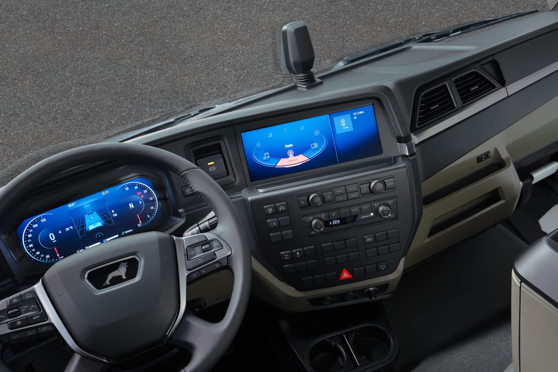 MAN-Fahrzeuginnenraum mit einem Lenkrad, hinter dem sich ein Bildschirm mit einem Abstandsmesser, einem Tachometer und einem Drehzahlmesser befindet. Zusätzlicher Bildschirm in der Mitte des Armaturenbretts mit einigen Unterhaltungsfunktionen und Tasten am unteren Rand.
                 