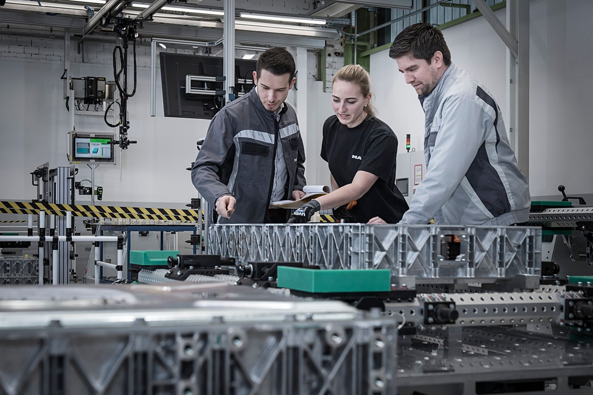 Drei Personen besichtigen eine MAN-Batterieproduktion in Nürnberg.